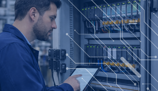 Engineer reviewing an open PLC control panel in an industrial facility